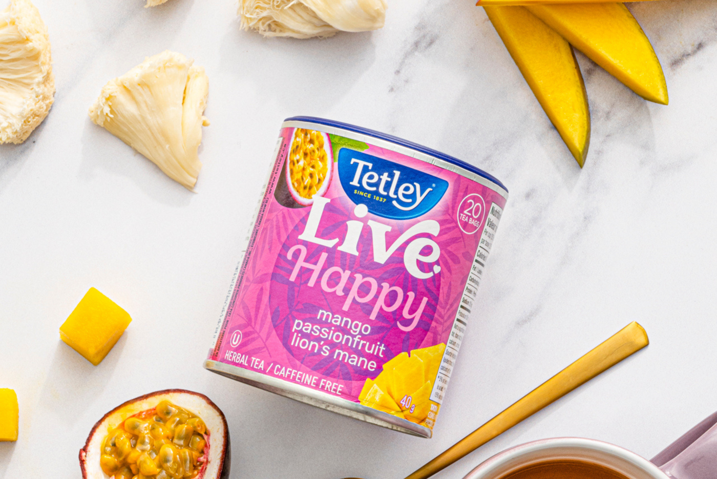 Canister of Tetley Live Happy Tea surrounded by fresh ingredients Mango, Passionfruit, and Lion's Mane